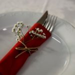 Elegant table setting with a red napkin, cutlery, and white flowers for a classy dining experience.