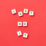 Motivational phrase 'Just Do It' spelled with Scrabble letters on a red background.